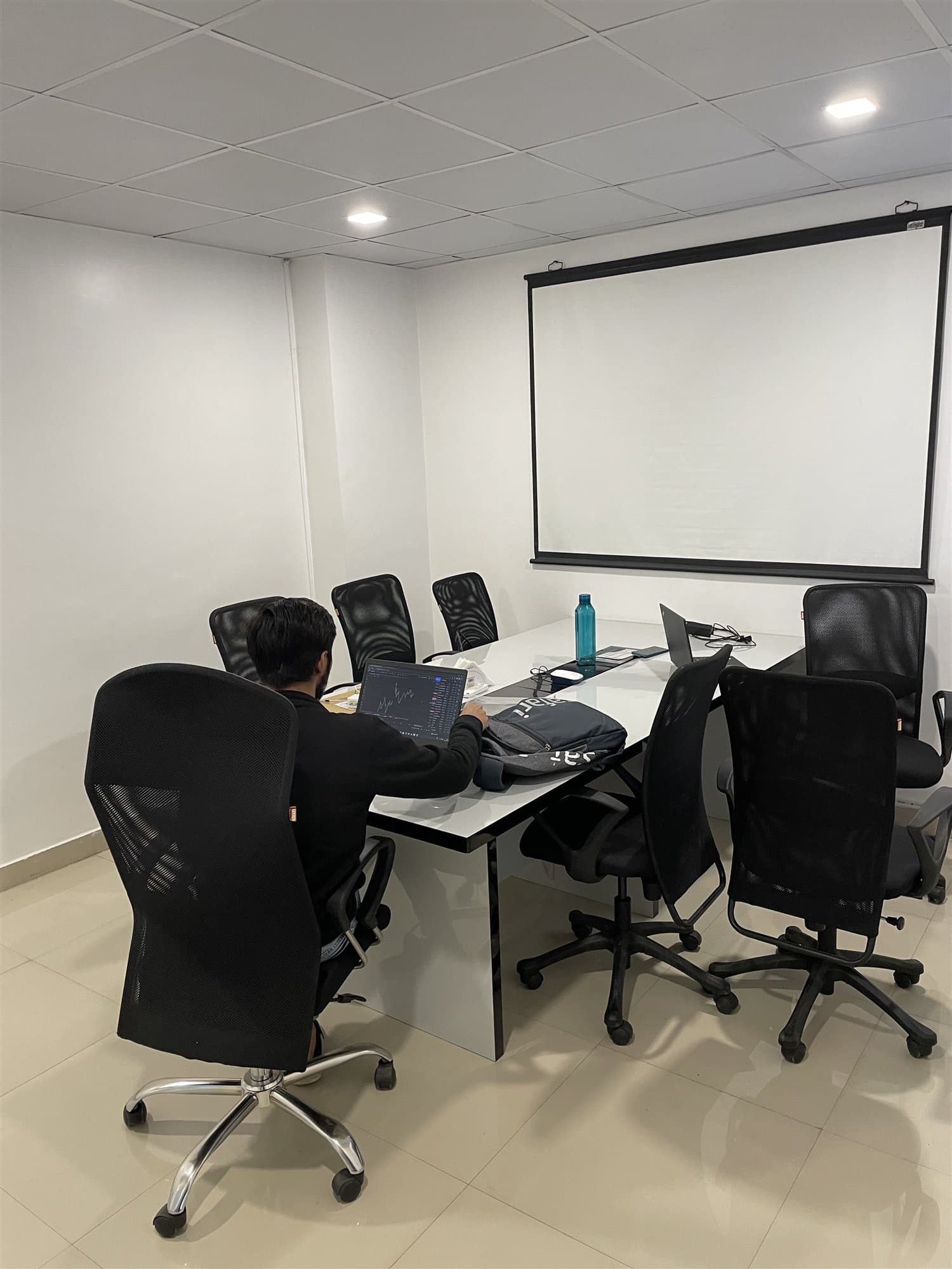 An engineer working at a laptop in the head office meeting room, beside a projection screen